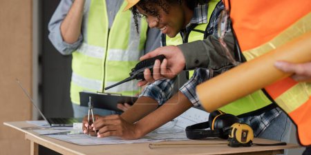Photo for Architect team working with blueprints for architectural plan, engineer sketching a construction project on table in working site. - Royalty Free Image