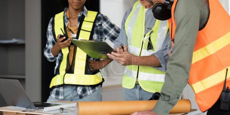 Photo for Architect team working with blueprints for architectural plan, engineer sketching a construction project on table in working site. - Royalty Free Image