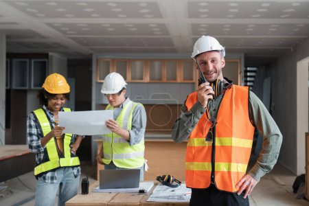 Téléchargez les photos : Portrait d'un ingénieur tenant un talkie-walkie et d'une ingénieure travaillant ensemble à l'inspection d'un ensemble domiciliaire sur le chantier. - en image libre de droit