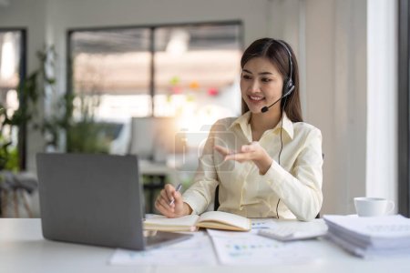 Photo for Portrait of happy smiling female customer support phone operator at workplace. Smiling beautiful Asian woman working in call center. - Royalty Free Image