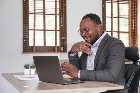 Téléchargez les photos : Homme d'affaires afro-américain utilisant son ordinateur portable tout en travaillant à distance de la maison. Concept de travail ou d'apprentissage en ligne. - en image libre de droit