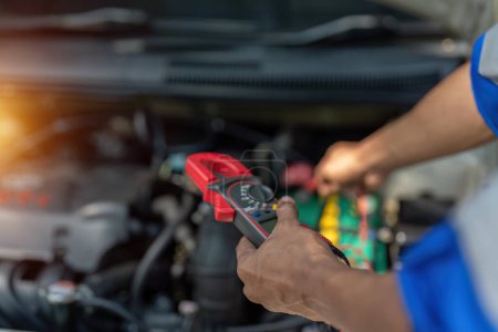 Photo for Close up technician uses multimeter voltmeter to check voltage level in car battery. Service and Maintenance car battery.. - Royalty Free Image