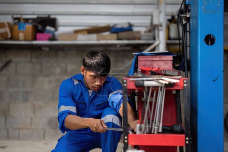 Téléchargez les photos : Portrait de positif asiatique auto mécanicien en uniforme posant après le travail, il est désireux de réparer les voitures, les automobiles. - en image libre de droit