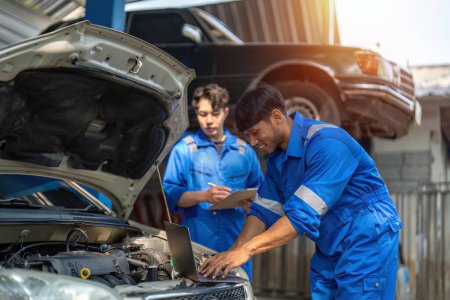 Photo for Mechanic man shows report to the asian coworker at garage, A man mechanic and his son discussing repairs done vehicle. Changing automobile business.. - Royalty Free Image