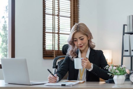 Téléchargez les photos : Jeune femme d'affaires souriante travaillant sur ordinateur portable portable tout en buvant une tasse de café marche. - en image libre de droit