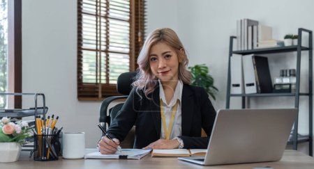Téléchargez les photos : Jeune femme d'affaires assis dans son bureau à la maison écrivant des notes. - en image libre de droit