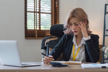 Foto de Mujer de negocios cansado y estresado con exceso de trabajo en el escritorio, mujer asiática con preocupado no idea con el análisis gráfico portátil y en la oficina. - Imagen libre de derechos