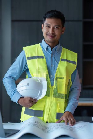 Photo for Asian engineer handsome man or architect looking forward with white safety helmet in construction site. - Royalty Free Image