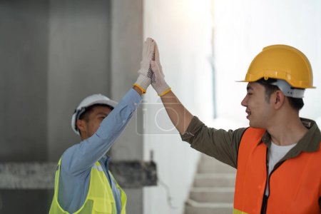Téléchargez les photos : Ingénieur un high five à son ami collègue sur le chantier de construction, les travailleurs célèbrent leur succès avec un high five, travail d'équipe. - en image libre de droit
