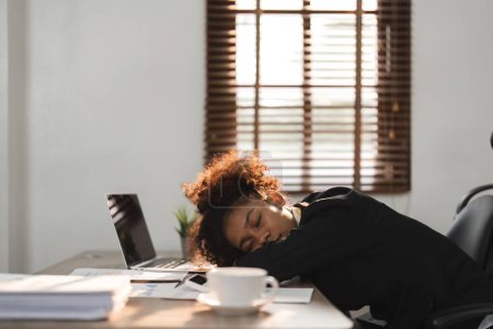 Photo for Sleepy and tired young black businesswoman or female office worker taking nap or sleep on her office desk. - Royalty Free Image