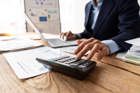 Téléchargez les photos : Homme d'affaires travaillant sur bureau avec l'aide d'une calculatrice pour calculer les chiffres, concept de comptabilité financière. - en image libre de droit