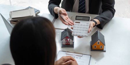 Téléchargez les photos : Les agents immobiliers parlent au client et offrent de bons taux d'intérêt et calculent les clients sur le financement hypothécaire - en image libre de droit