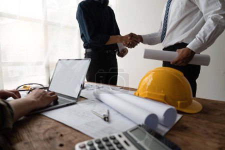 Photo for Professional Asian male engineer shaking hands with architect after meeting for agreement or contract. - Royalty Free Image
