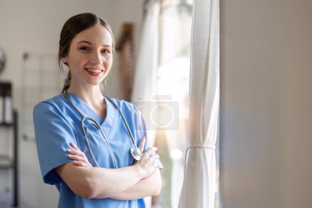 Photo for Smiling female doctor with stethoscope around neck standing with arms crossed. She is dedicated and experienced doctor. - Royalty Free Image