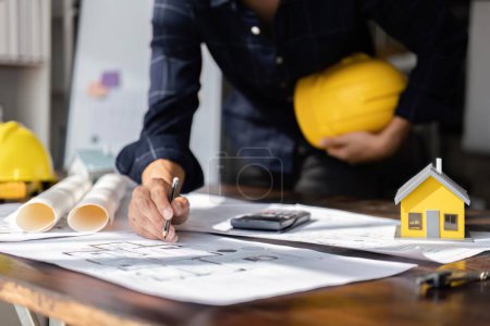 Photo for Engineer checks construction blueprints on new project with engineering tools at desk in office. - Royalty Free Image