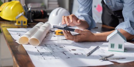 Photo for Engineer checks construction blueprints on new project with engineering tools at desk in office. - Royalty Free Image