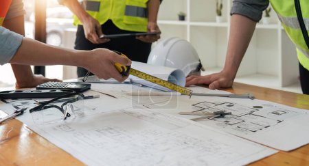 Téléchargez les photos : Ingénieur gens réunion de travail et pointant vers un plan dans le bureau pour discuter. Outils d'ingénierie et concept de construction. - en image libre de droit