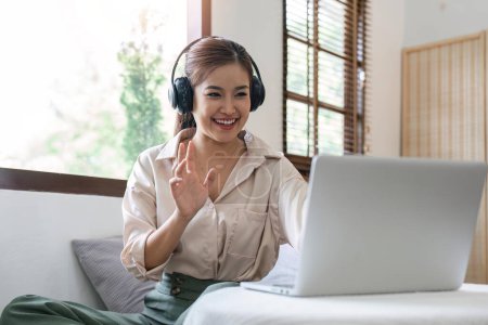 Photo for Young happy smiling woman in casual clothes sitting on sofa work online talk by video call with laptop pc computer wave hand rest relax indoors at home People lifestyle leisure concept. - Royalty Free Image