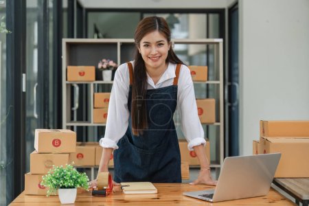 Téléchargez les photos : Heureuse asiatique femme travailler à partir de l'emballage à la maison, emballage marketing en ligne et livraison, concept de PME. - en image libre de droit