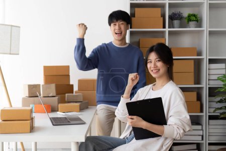 Foto de Jóvenes mujeres asiáticas parejas son felices juntos después de vender cosas en línea con éxito. Atractivo jóvenes asiáticos parejas en línea de compras mientras se trabaja desde casa en el ordenador portátil. - Imagen libre de derechos
