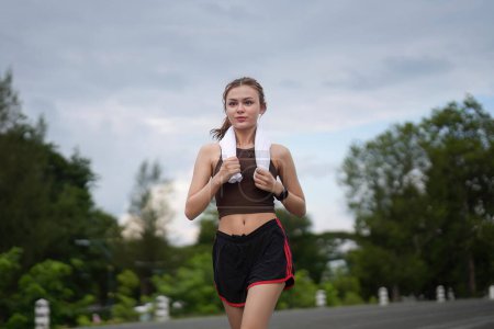 Téléchargez les photos : Jeune belle coureuse athlétique attrayante court dans le parc vert jogging. Concept de mode de vie sain et actif. - en image libre de droit
