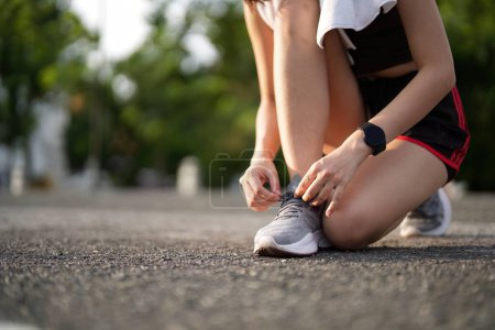 Téléchargez les photos : Des chaussures de course. fermer lacets athlète féminine attacher pour le jogging sur la route. Cravates de coureur se préparent pour l'entraînement. Style de vie sportif. espace de copie. - en image libre de droit