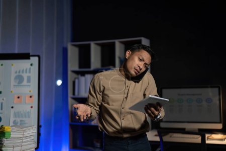 Téléchargez les photos : Surmenage jeune employé de bureau asiatique travaillant sur ordinateur portable heures supplémentaires dans le bureau la nuit. - en image libre de droit