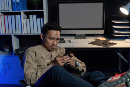 Foto de El exceso de trabajo joven empleado de oficina asiática que trabaja en el ordenador portátil horas extras en la oficina por la noche. - Imagen libre de derechos