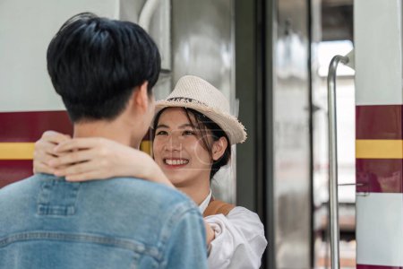 Téléchargez les photos : Petite amie positive embrasser homme heureux tout en localisant près du train. - en image libre de droit