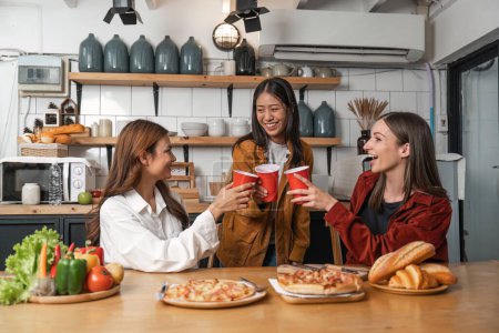 Photo for Happy group of friends drinking at kitchen girl friend having dinner sitting down lifestyle with girls hanging out on weekend. - Royalty Free Image