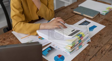 Photo for Close up of businesswoman hands using a calculator to check company finances and earnings and budget. Business woman calculating monthly expenses, managing budget, papers, loan documents, invoices. - Royalty Free Image