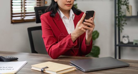 Téléchargez les photos : Jeune femme d'affaires asiatique avec un smartphone au bureau. - en image libre de droit
