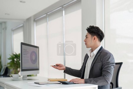 Photo for Handsome smiling businessman sitting in office and working on laptop screen. - Royalty Free Image