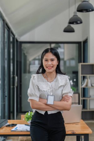 Téléchargez les photos : Belle entreprise asiatique femme debout dans le bureau, regardant la caméra et souriant. - en image libre de droit