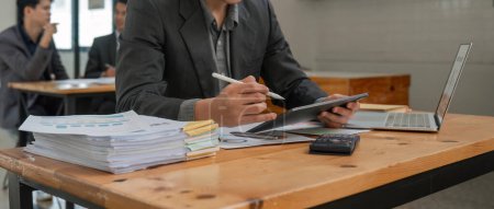 Foto de Concepto de contabilidad empresarial, hombre de negocios con calculadora con computadora portátil y tableta en la oficina. - Imagen libre de derechos