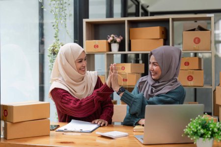 Téléchargez les photos : Deux femmes musulmanes affaires en ligne travaillant ensemble, montrant un geste puissant geste impressionnant. - en image libre de droit