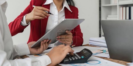 Photo for Businesspeople using a tablet and calculator to analyzing numbers on a companys financial documents, analyzing financial data to plan how to grow the company. Financial concept. - Royalty Free Image