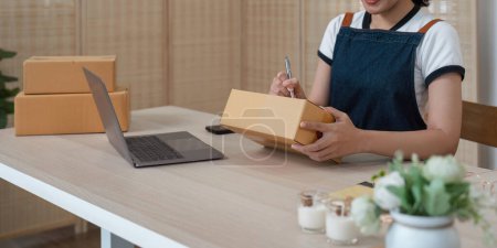 Téléchargez les photos : Jeune femme d'affaires asiatique travaillant à la maison préparant la boîte de paquet de PME pour la livraison à la maison de petite entreprise. - en image libre de droit