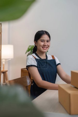 Photo for Young business woman working online ecommerce shopping at her shop. Young woman seller prepare parcel box of product for deliver to customer. Online selling, ecommerce. - Royalty Free Image