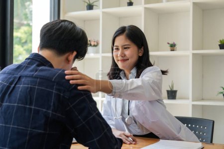 Photo for Asian female doctor giving hope and encourage to stressed man patient at hospital. Smiling doctor woman touching on patient shoulder to support take care and helping . Supported and Encouraged. - Royalty Free Image