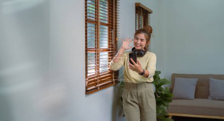 Foto de Las mujeres asiáticas está utilizando el teléfono celular para hacer una videollamada de comunicación inalámbrica alegre en casa.. - Imagen libre de derechos