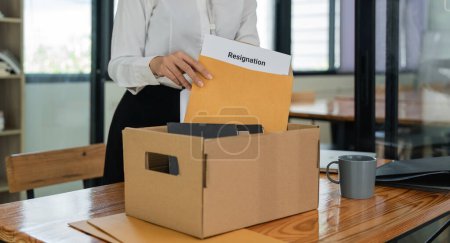 Téléchargez les photos : Asiatique femme employée de bureau portant une boîte en carton avec ses affaires personnelles et lettre de démission. - en image libre de droit