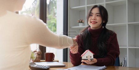 Foto de Agentes inmobiliarios y clientes se dan la mano para felicitar a la firma de un contrato para comprar una casa con tierra. - Imagen libre de derechos