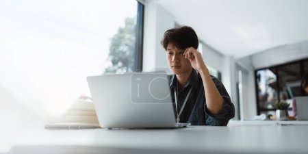 Photo for Businessman stressed with work and deadlines Stressed businessman with laptop sitting at desk in office. - Royalty Free Image