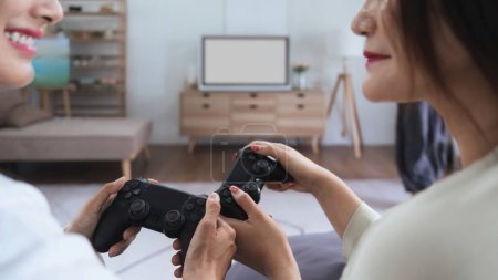 Photo for Asian homosexual couple of lesbian woman sitting on couch in living room at home enjoy and excited holding console playing game together. - Royalty Free Image