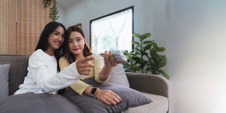 Téléchargez les photos : Asiatique jeune femme homosexuel lesbienne couple mis sur pull assis sur canapé pour regarder le cinéma dans le salon à la maison. - en image libre de droit