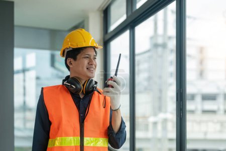 Téléchargez les photos : Asiatique mâle ingénieur debout sur le chantier de construction et de communiquer avec talkie walkie. - en image libre de droit