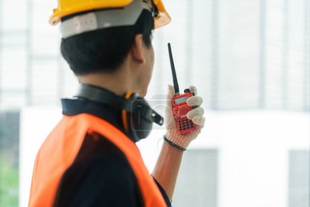 Téléchargez les photos : Asiatique mâle ingénieur debout sur le chantier de construction et de communiquer avec talkie walkie. - en image libre de droit