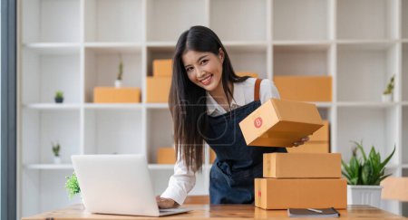 Photo for Small business entrepreneur SME, Asian owner holds a package in box, ready for delivery to a customer who orders online, ecommerce concept. - Royalty Free Image
