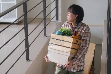 Foto de Feliz hombre asiático y su amigo llevando sus pertenencias arriba mientras se trasladan a un nuevo apartamento.. - Imagen libre de derechos